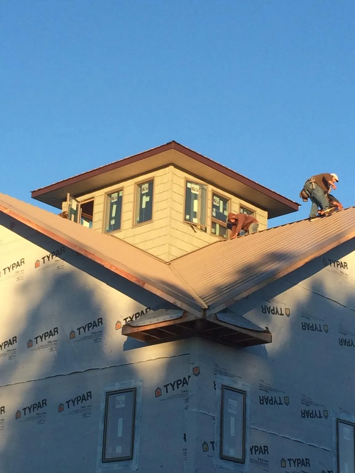 Roofers working around a rooftop cupola on a new metal roof at sunset — Roof Waterproofing in Fleetwood by Roofing Brothers